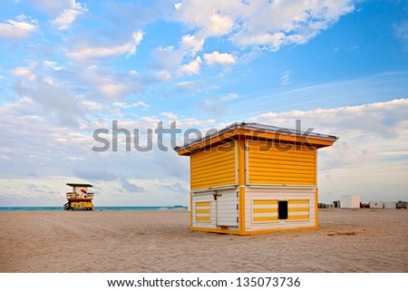 Summer scene in Miami Beach Florida, with a colorful lifeguard house in a typical Art Deco architecture, at sunset with ocean and sky in the background.