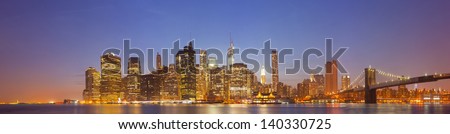 New York City, USA colorful night skyline panorama with illuminated landmark buildings in downtown Manhattan business and residential districts and famous Brooklyn Bridge