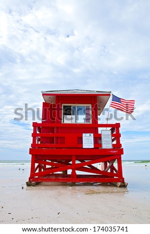 Siesta Key Beach, Florida USA, red lifeguard house with American flag on a beautiful summer day with ocean and blue cloudy sky