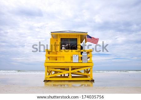 Siesta Key Beach, Florida USA, yellow lifeguard house on with American flag a beautiful summer day with ocean and blue cloudy sky