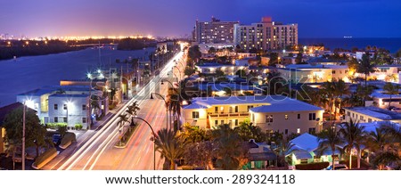 Hollywood Florida, USA. Night panorama of hotels, buildings and moving traffic by the beach with ocean in the background