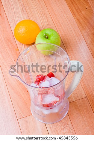 Fresh Orange, apple Strawberries and ice in a blender, for fruit milkshake