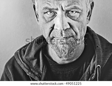 Closeup black and white character portrait of a man with blue eyes, dressed in an old hooded jacket looking at the camera with questioning and suspicious facial expression