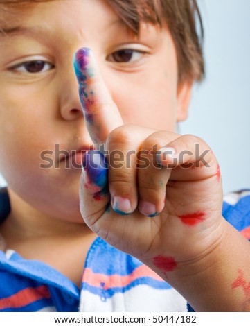 Curious Three year old Child is looking at his painted finger. Closeup portrait on white background