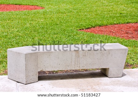 Modern concrete benches and path in a public park with green grass on a beautiful spring day