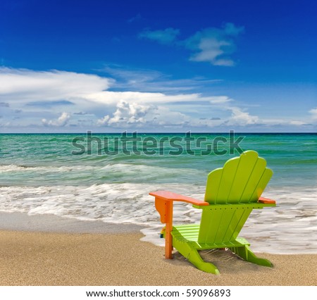 Colorful green and orange lounge chair at the tropical beach in Miami Florida with beautiful ocean waters and blue sky.