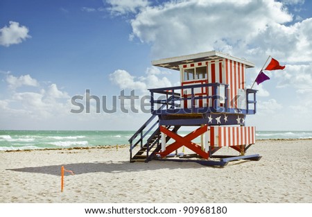 Miami Beach, Florida colorful lifeguard building painted with stripes and stars resembling the USA flag. Beautiful sunny day with blue sky and ocean in the background