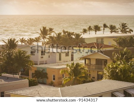 Summer scene with colorful buildings, palm trees, hotels and ocean in the background in Hollywood Beach, Florida bathing in golden light just after sunrise
