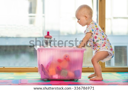 baby girl in creche kids room with big box of toy toys