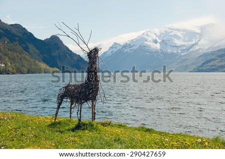 The picture of the deer made from a twigs on the background of the fjords mountains