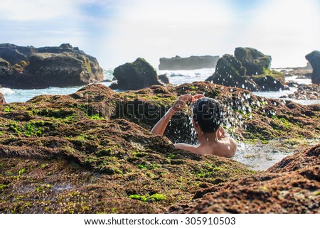 A traveler plays water inside the rock\'s hole beside the beach