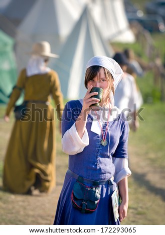 GRUNWALD - July 16: Medieval fashion, middle ages woman having a drink at meeting at Battle of Grunwald 601th anniversary, 4000 reenactors,1200 knights, near 20k viewers. July 16 2011 Poland