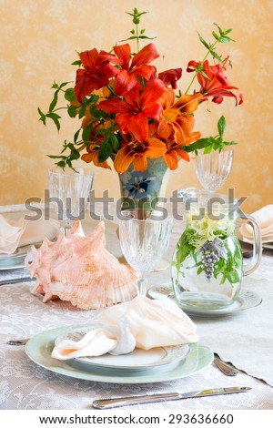 Summer time dinner table setting. Bouquet in vintage English vase. Seafood. Bird shaped napkin rings. In bright natural light. Herbal tea in vintage jar.