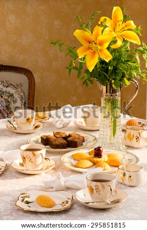 Summer time dinner table setting Tablescaping. Bird shaped napkin rings. Warm late afternoon sunlight. Antique English teacups and plates from 1940s. Madeleine cake, brownie.