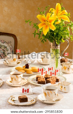 Celebrating Canada Day, Civic Holiday. Afternoon tea table setting Tablescaping.  Bouquet in vintage Wine decant.  Warm late afternoon sunlight. Antique English teacups and plates from 1940s.