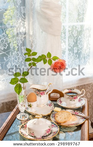 Breakfast - room service. Vintage / antique style interior design. Matching patterns of tableware and the curtains. Fine bone china. Cross stitch tea tray. Tea room. Portrait orientation.