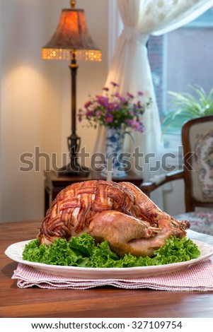 Thanksgiving Turkey Dinner. Roast turkey covered with bacon bacon. Retro / antique setup. Antique furniture, pink daisy flowers in  antique blue and white china vase.
