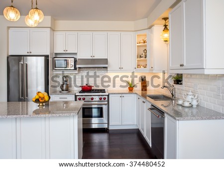 Professionally designed new kitchen with touch of retro. Professional gas range and hood, white cabinet,  antique ceiling lamp, fine bone china teacups in cabinets. Interior design ideas.