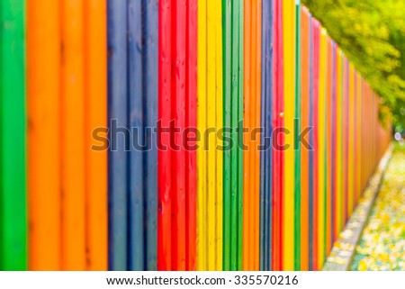 Multi colored rainbow wooden fence in autumn, garden background, soft focus, shallow depth of field