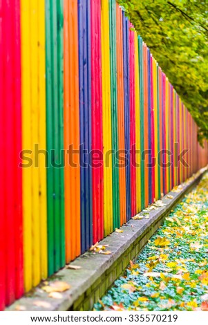 Multi colored rainbow wooden fence in autumn, garden background, soft focus, shallow depth of field