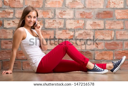 girl casual design with the phone sitting on a brick wall