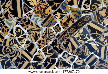 Close-up of the ceramics in Park Guell Barcelona created by Gaudi. Dark and golden.