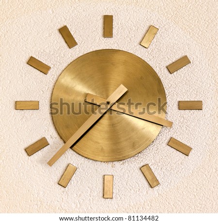 Brass clock on the wall of beige