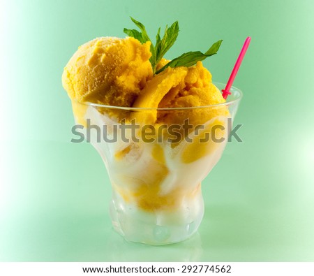 Mango sorbet with mint in glass bowl on green background