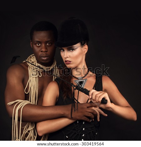 Fashion studio photo of a sensual couple;  woman in a black swimsuit handmade with her man  on black background