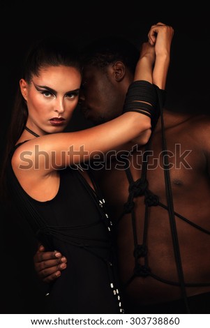 Sexy couple; woman in a black swimsuit handmade with her man, girl hands tied with rope
