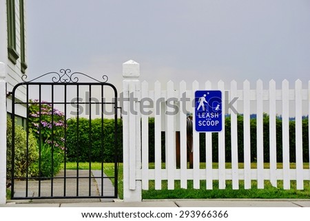 Pick Up After Your Dog Sign on White Picket Fence
