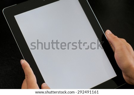 Woman holding tablet computer with both hands on dark background