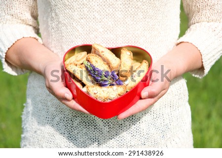 Woman with cookies in the red tin box in heart shape