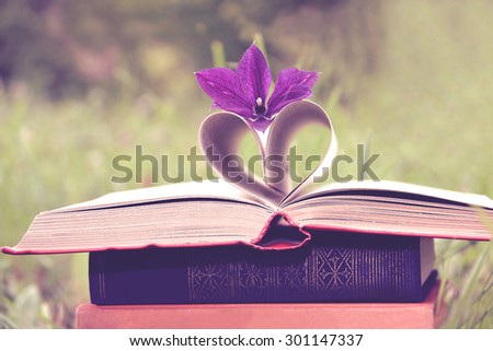Open book with summer clematis flower on nature background. Knowledge is power. Vintage style