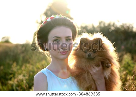 Portrait of young beautiful girl in the blue dress with pomeranian dog. Dog man\'s best friend. Romantic woman with little dog. Pretty free woman