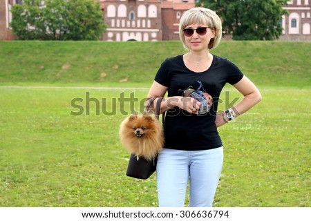 Portrait of beautiful mature woman and her lovely dog. Pomeranian dog in bag. Stylish woman in sunglasses 50s years. Modern woman. Lovely middle-aged blond woman. Dog man's best friend