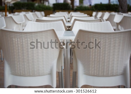 Perfectly aligned chairs and tables on an open air terrace in a holiday resort