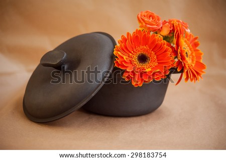 cast iron pot with orange roses and gerberas