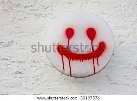 Spray painted happy face on a white lamp on a white brick wall