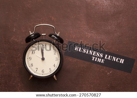 alarm clock showing almost twelve o\'clock and indicating to have business lunch