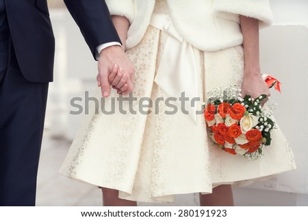 bride and groom holding hands, bridal bouquet of flowers in hands of the bride. selective focus