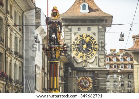 BERN, SWITZERLAND - SEPTEMBER 23, 2014: Old statue view in the shopping alley with the famous clocktower of Bern in Switzerland. The Zytglogge is one of Bern\'s most recognisable symbols.