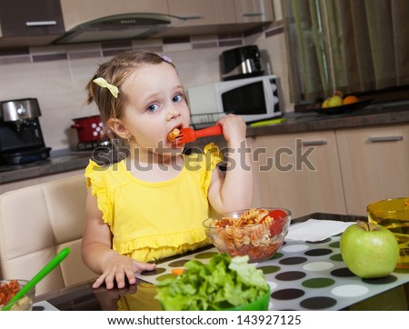 Little girl who eat healthy food in the kitchen