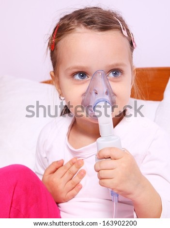Little girl making aerosol treatment with a rubber mask