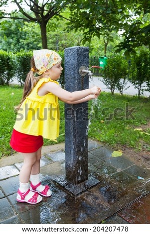 Girl who wash their hands at a fountain in the park