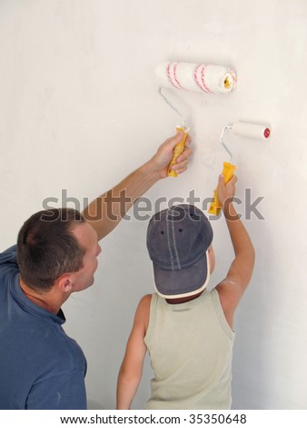 child and father painting wall together