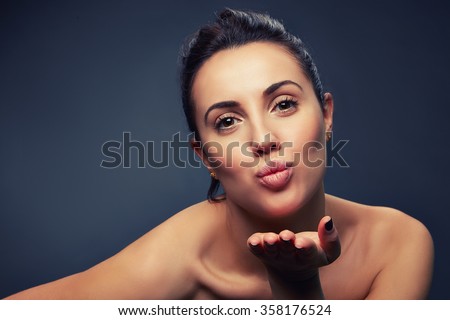 Attractive beautiful young caucasian woman with perfect skin showing air kiss. Open shoulders. Toned