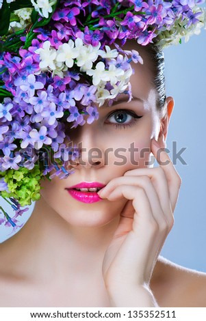 Black and white painted close-up portrait of girl with stylish makeup and flowers around her face