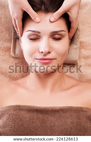 Beautiful young relaxed woman enjoy receiving face massage at spa saloon