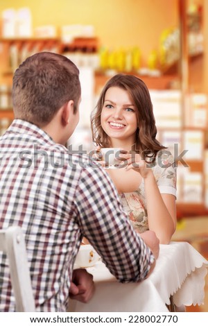 Seducing beautiful woman looking at her lover with coffee cup. Having romantic talk